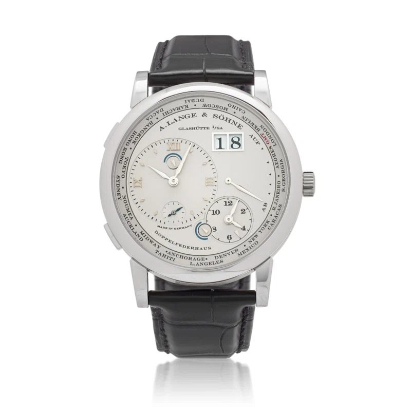 Lange 1 Time Zone (المرجع 116.025). ساعة يد من البلاتين بقطر 41.9mm، بحركة ميكانيكية ذات تعبئة يدوية، مع التاريخ وday/night indicator واحتياطي الطاقة وtime-zone function.